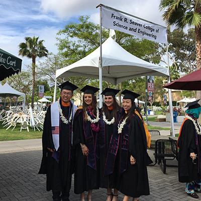 Four graduate students in cap and gown